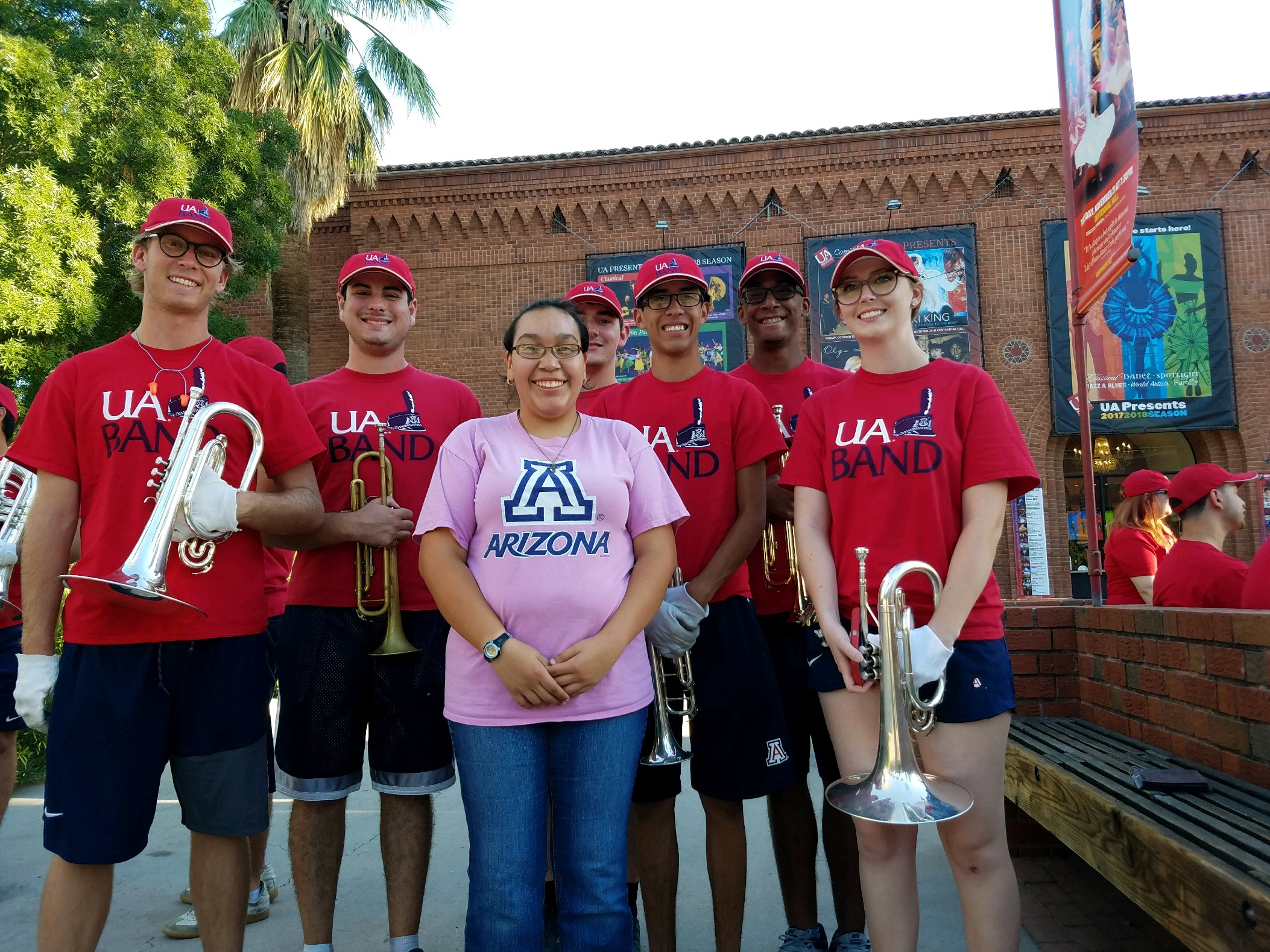 female student posing with UArizona marching band during pep rally