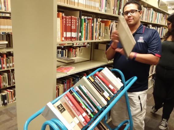 male student shelving books in university library