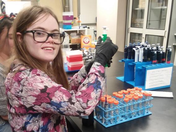 smiling female student loading chemicals into test tubes