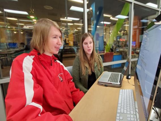 Project FOCUS student and peer mentor work on a computer on campus