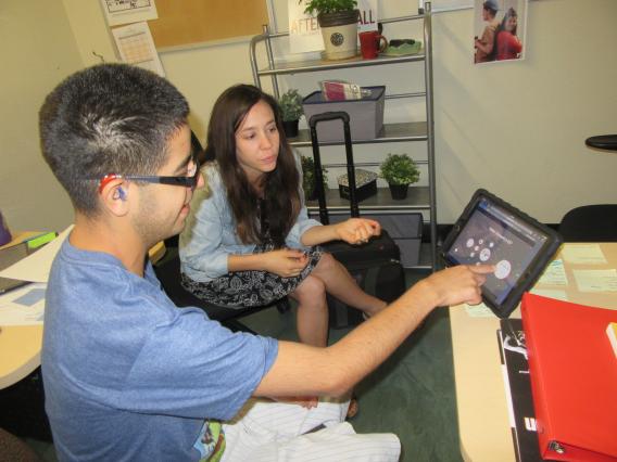 male student using tablet with female teacher support