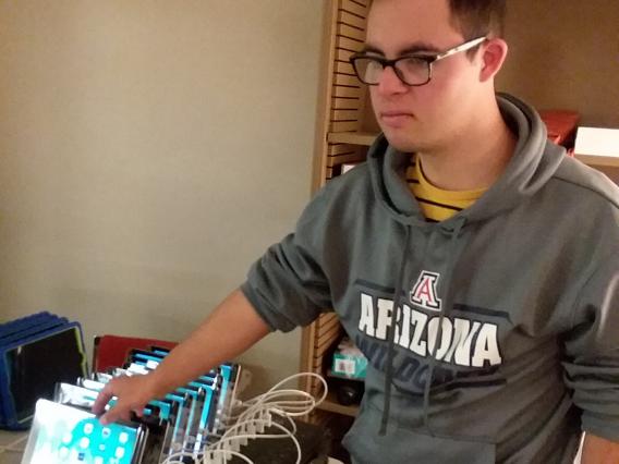 male student grabbing one iPad from a stack of tablets