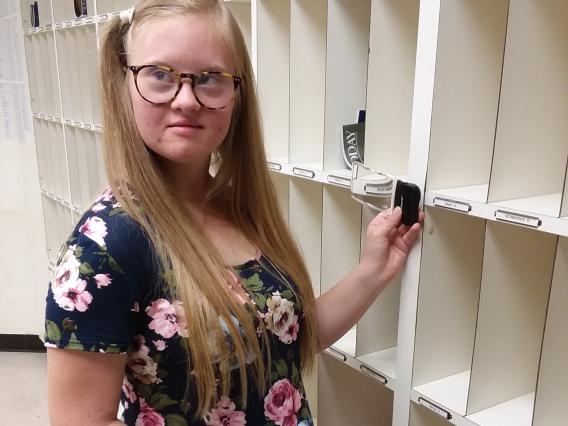 female student using a magnifier as she sorts mail into boxes