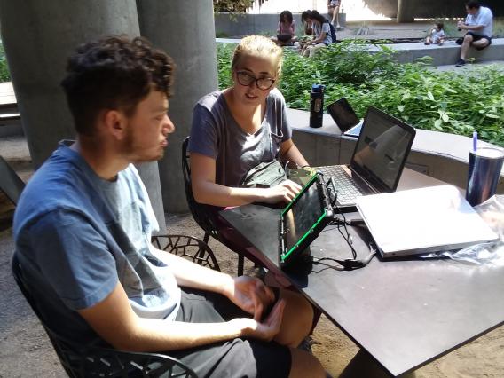 male student using AAC device with female peer mentor support