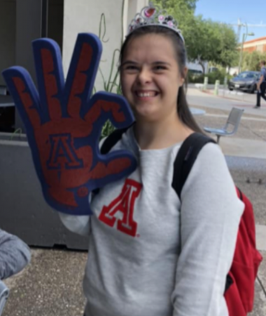 student smiling and holding up a Wildcat foam hand